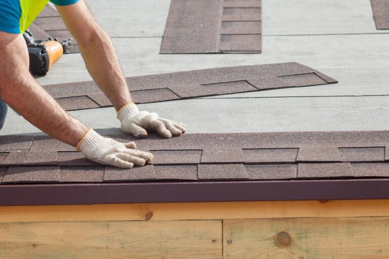 Roofer fitting new asphalt shingles by hand