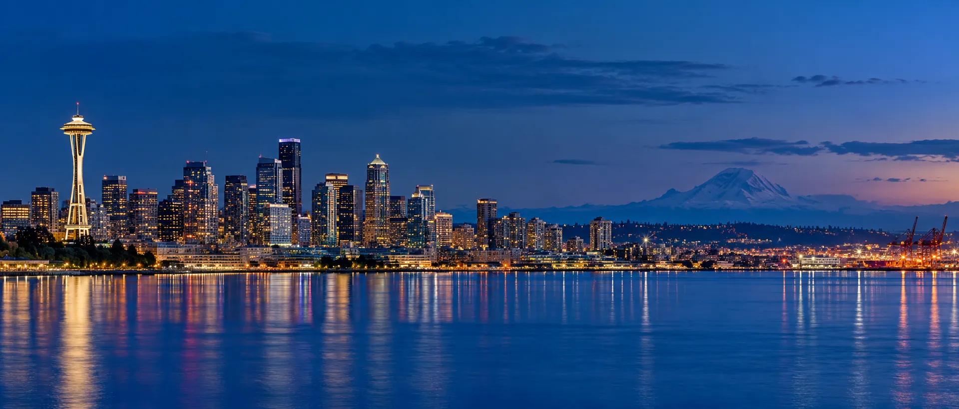 Seattle skyline at dusk across Elliott Bay with Mount Rainier